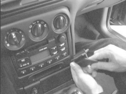 En person arbetar med bilens instrumentbräda, troligtvis radio eller kontrollpanel.