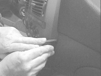 En person använder verktyg för att justera något på bilens interiör.