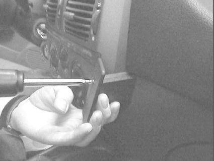 En person använder en skruvmejsel för att ta bort en del av bilens interiör.