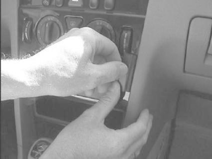 En hand justerar en plastdel i centrumkonsolen på en Mercedes Benz C-Klass.