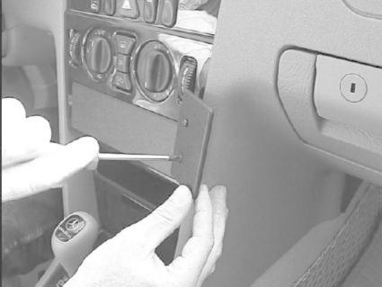 En hand som använder en skruvmejsel på en panel i en bil.