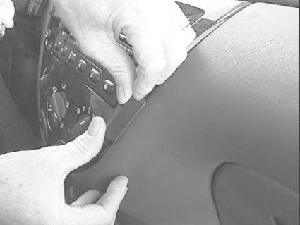 En person monterar en del av instrumentpanelen i en Ford Focus 99-04.