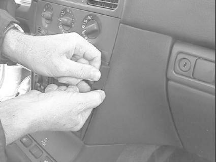 Händer monterar eller fäster komponenter i Volvo S40s interiör.