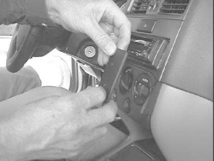 En hand fäster en monteringsbygel på en bils instrumentpanel.