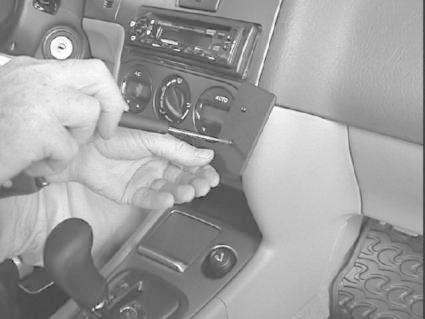 En hand skruvar fast en del i bilens interiör.