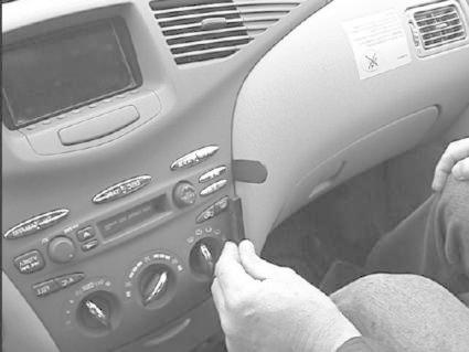 En hand justerar bilens stereo- eller klimatanläggningskontroller.