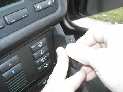 En hand justerar en del på instrumentbrädan i en BMW E39.