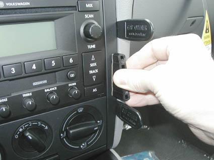 En hand installerar en del i en bils stereokonsol.