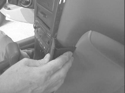 En hand fäster en vinklad monteringsbygel i en bilinteriör.