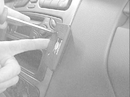 En hand som justerar en enhet på bilen, troligtvis stereo eller kontroller.