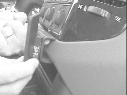 En hand tar en vinklad del från en bilpanel.