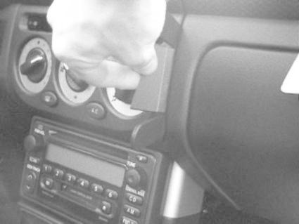 En hand installerar en montering på instrumentpanelen i en bil.