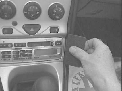 En hand håller en svart kloss vid en bils konsol.