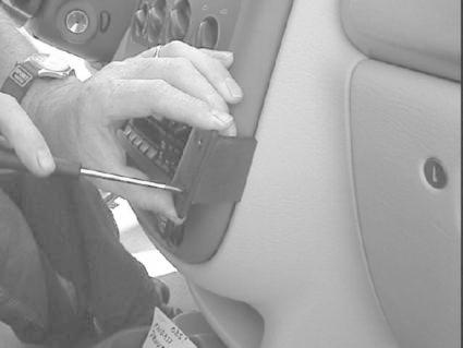 En hand arbetar med att installera eller ta bort en del av bilens inredning.