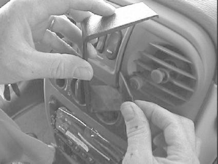 Händer monterar en del av instrumentpanelen i en Chrysler PT Cruiser.