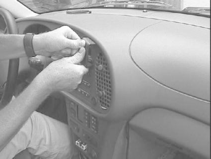 En person installerar eller justerar en del på instrumentpanelen i en Saab 9-3.