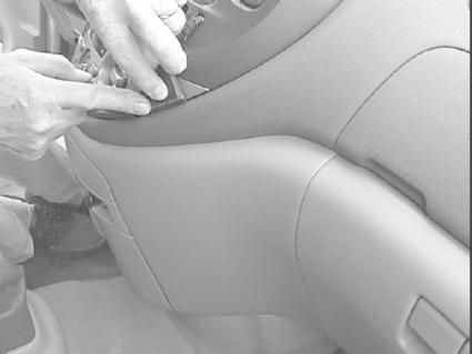 En person arbetar med bilens inredning, troligtvis för att reparera eller justera något.