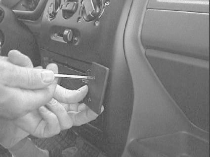 En hand installerar en monteringsbygel i en bil interiör.