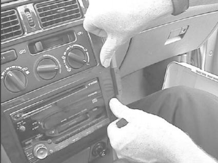 En hand tar bort en panel från bilens instrumentbräda.