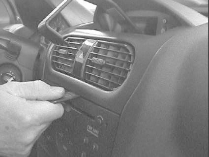 Bild som visar en hand som håller en skrapa nära luftutblåsning i en Opel Corsa.