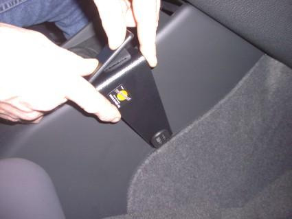 En hand håller i en vinklad del av bilen, troligtvis en del av interiören.