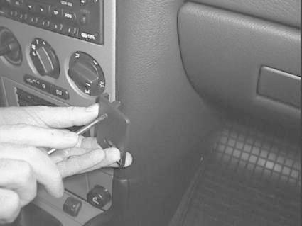 En hand använder ett verktyg för att justera en del i bilen.