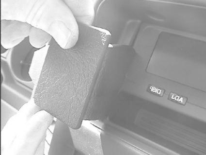 En hand håller i en svart ficka som placeras i en bilinteriör.