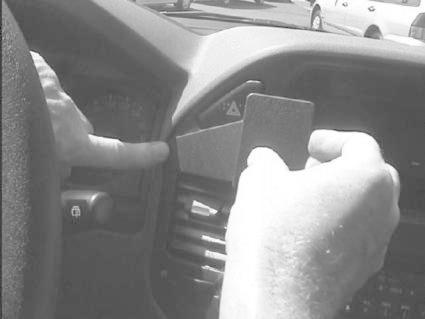 En person pekar och håller något vid bilens instrumentbräda.