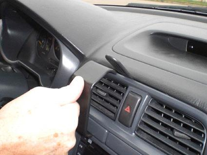 En hand som håller i en del av instrumentbrädan på en Subaru Impreza 01-04.