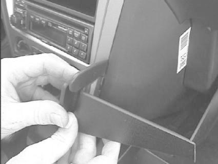 Hand som håller i en svart plastdel, troligtvis en bilkomponent.