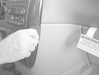 En hand justerar en komponent i en bilinteriör.