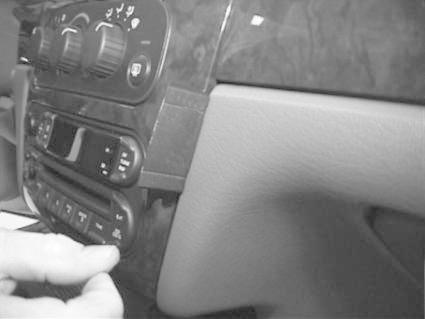 En hand justerar ljudkontroller i en bilinteriör för Chrysler Stratus.