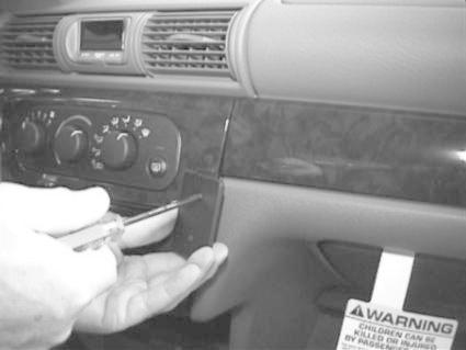 En hand håller i en skruvmejsel nära en bilpanel.