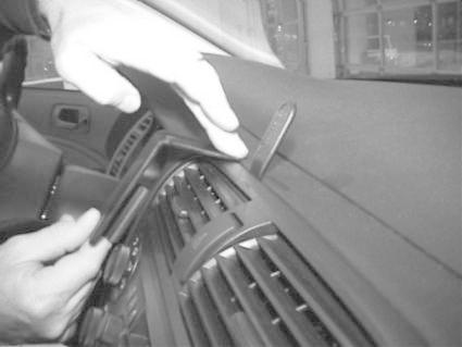 En hand installerar en monteringsbygel på instrumentbrädan i en bil.