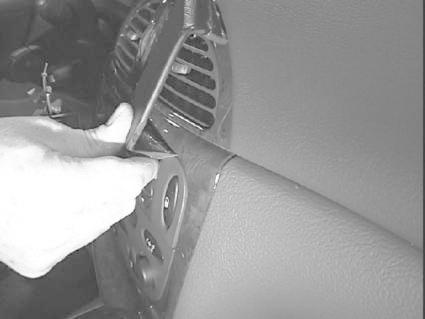 Bild visar en hand som arbetar med en del av bilens interiör, möjligtvis ventilation.