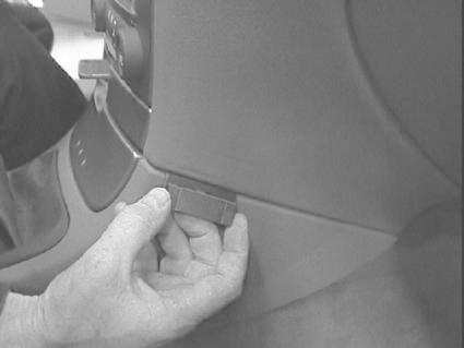 En hand håller en liten modul nära instaplatserna i en bil.