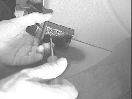 En hand håller en skruvmejsel och arbetar med en del av Renault Laguna 01-04.