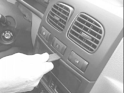 En hand som använder ett verktyg nära bilens kontrollpanel.