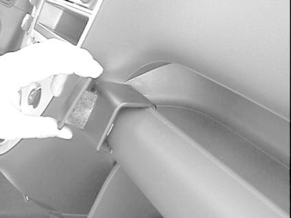 En hand håller i en del av bilen, troligtvis en inredningskomponent.