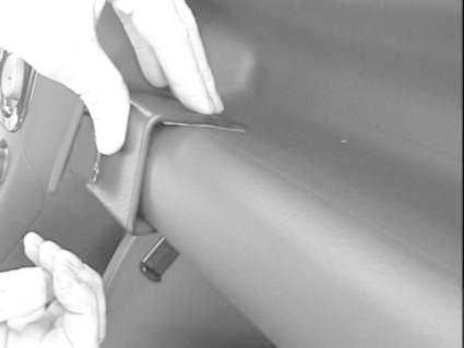 En hand monterar en vinklad bygel på insidan av en bil.