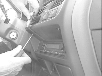 En person använder en skruvmejsel på en del av bilens instrumentpanel.