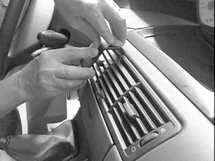 Händer justerar luftutblås i en bilinteriör.