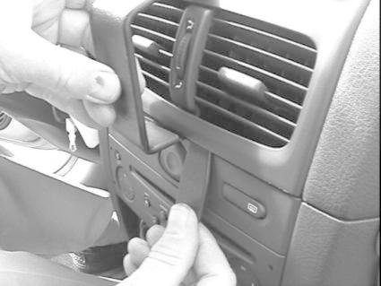 Hand som justerar en del av bilens instrumentpanel, troligtvis en ventil eller kontroller.