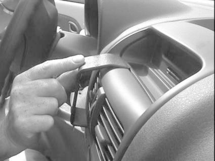 En hand håller i en del av bilens interiör, troligen en luftventil.
