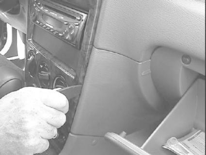 En hand som installerar en monteringsbygel i en bils interiör.