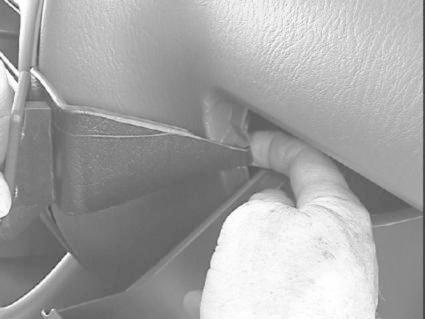 En hand som pekar på en försänkning i en bilinteriör.