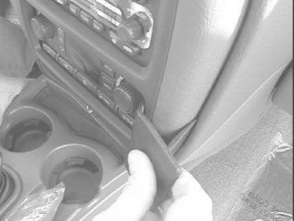 En hand håller i en del av bilens interiör, nära växelspak och kontroller.