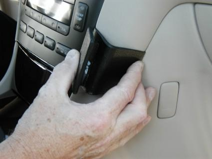 En person fäster en vinklad monteringsbygel vid en bilinteriör.