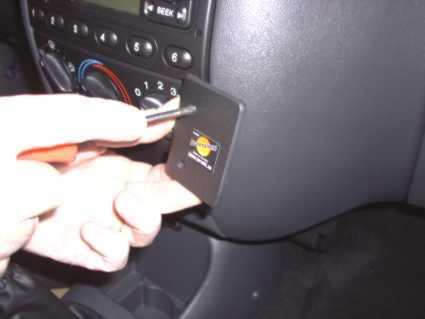 En hand håller en skruvmejsel mot en panel i en bil.