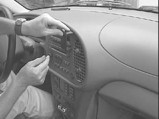 En person installerar träpanel i Saab 9-3:s instrumentbräda.